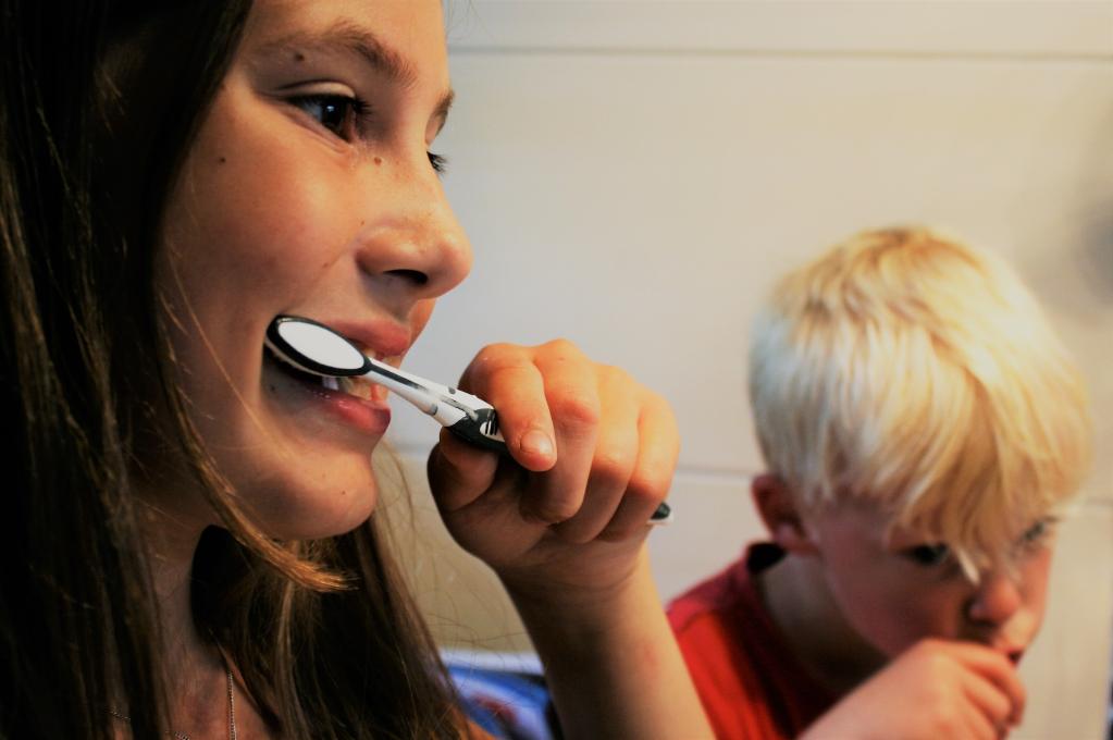 Photo of a child brushing their teeth with their Mum