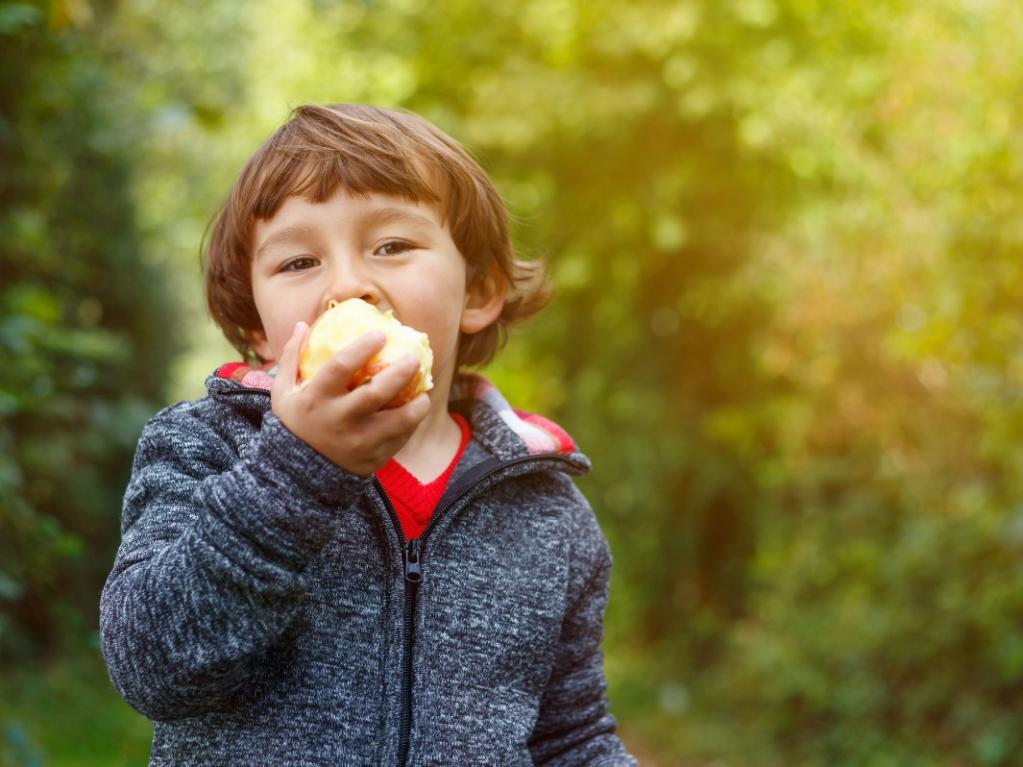 Photo of a child eating an apple outside