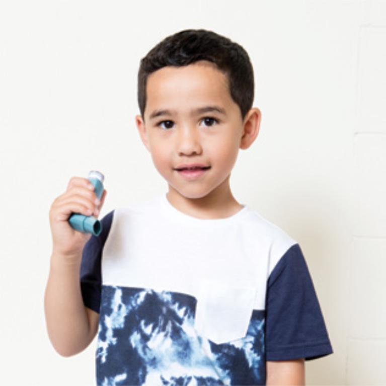 A child holding an inhaler, ready to use it.