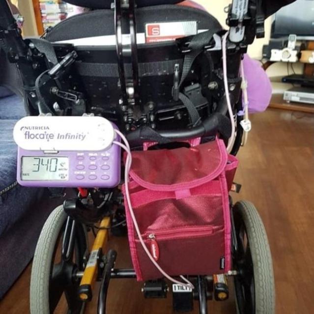 A photo of tube feeding equipment on the back of a wheelchair 
