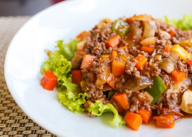 Savoury mince with diced vegetables served on a white plate with lettuce leaves.