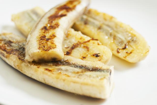 Grilled banana halves with browned edges served on a white plate.