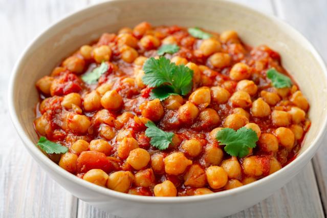 Bowl of chickpeas in a spicy tomato sauce topped with fresh coriander leaves.