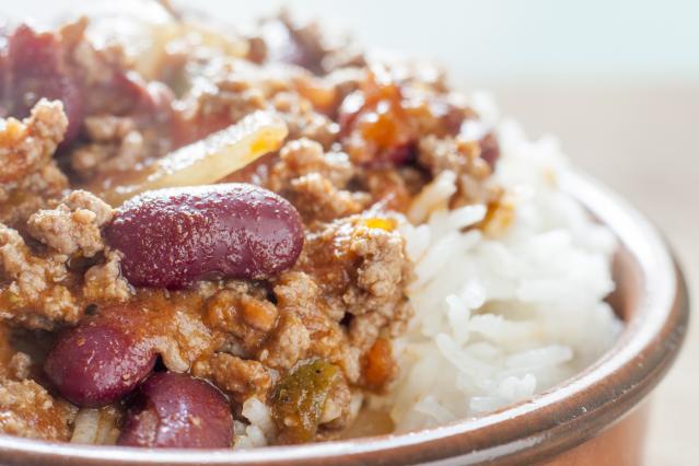 Chilli con carne with kidney beans and minced meat served over white rice in a bowl.