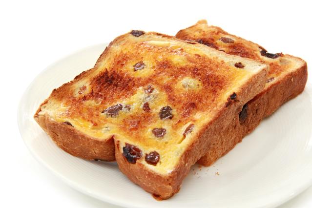 Two slices of toasted fruit bread with melted butter on a white plate.