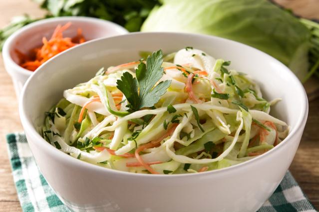Bowl of coleslaw made with shredded cabbage, carrot and parsley.