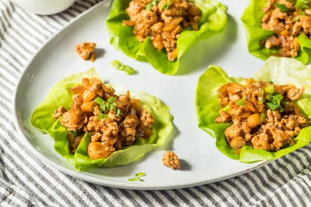 Lettuce cups filled with minced pork, onion and vegetables on a plate.