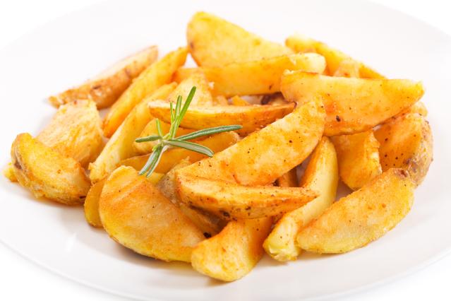 Plate of roasted potato wedges seasoned with herbs and spices.