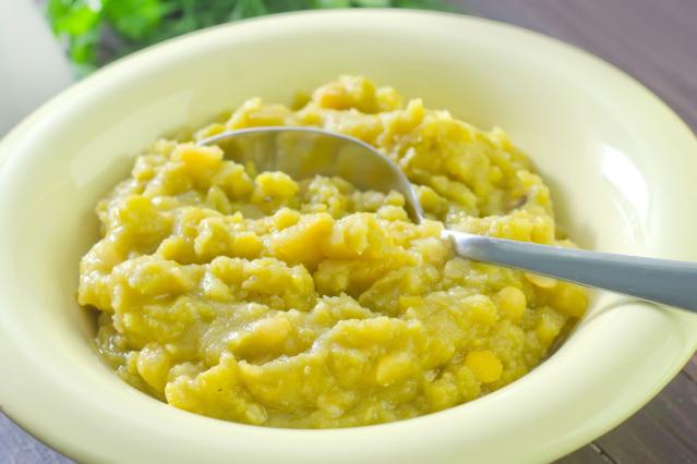 A bowl of thick yellow lentil purée with a spoon resting in the bowl.