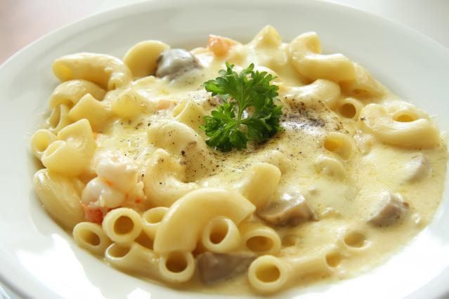 A bowl of creamy macaroni cheese topped with parsley and black pepper.