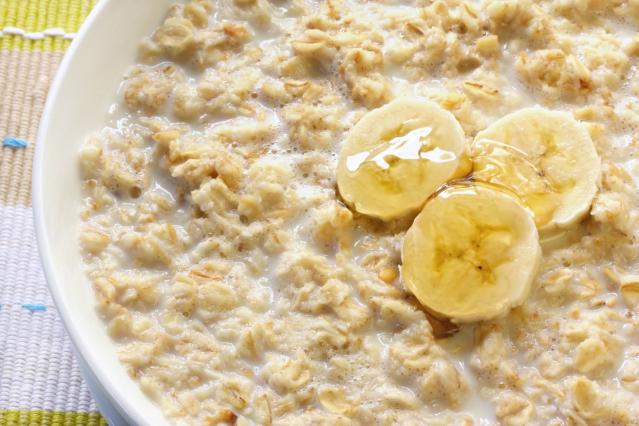 A bowl of creamy porridge topped with banana slices and a drizzle of honey.