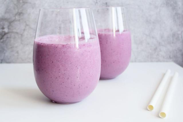 Two glasses of berry and puha smoothie on a white table beside reusable straws.