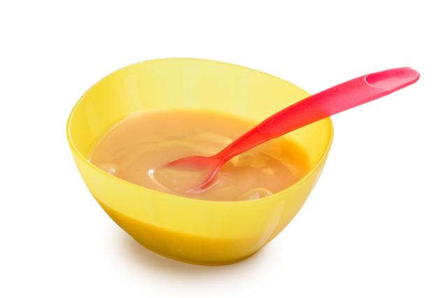 A bowl of smooth roasted vegetable purée with a spoon resting inside.