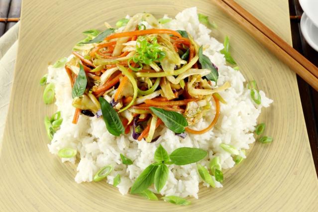 A vegetable stir-fry with carrot, cabbage, and herbs served on white rice in a bowl.