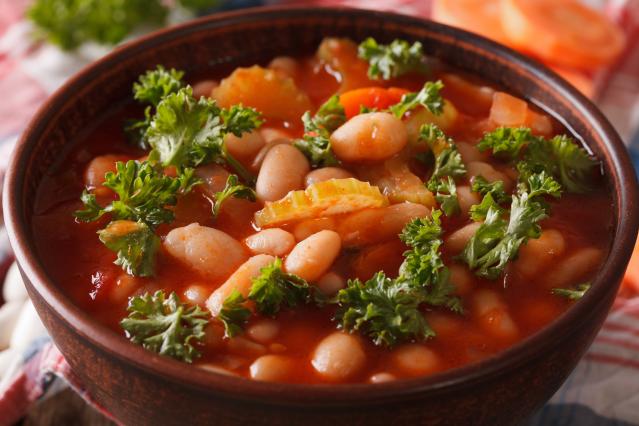 Bowl of tomato and bean soup with white beans, celery and parsley.