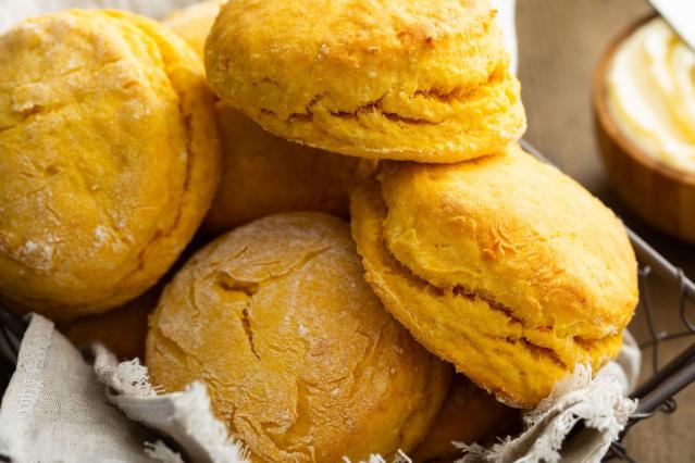 Freshly baked golden scones stacked in a basket lined with a cloth.