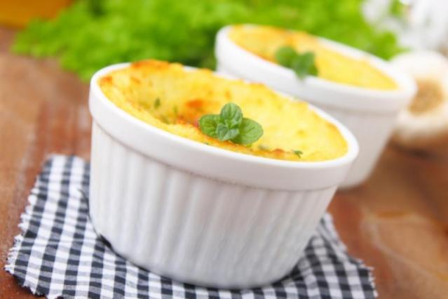 Two white ramekins filled with golden baked pastry-less pie topped with melted cheese and parsley.