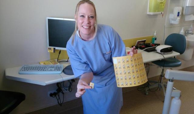 Dental assistant smiling holding a sticker