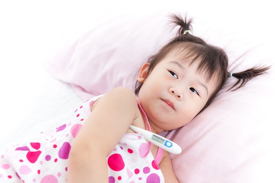 Little girl lying on sickbed with digital thermometer under her arm
