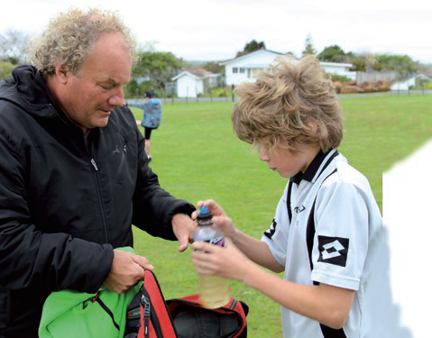A dad and a teenage boy at a soccer game