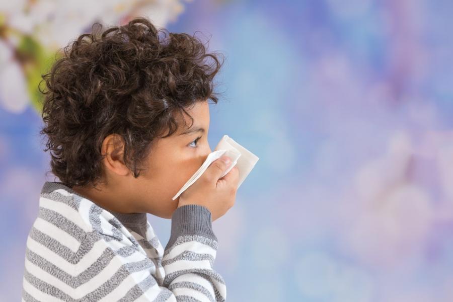 Boy with a virus blowing his nose into a tissue