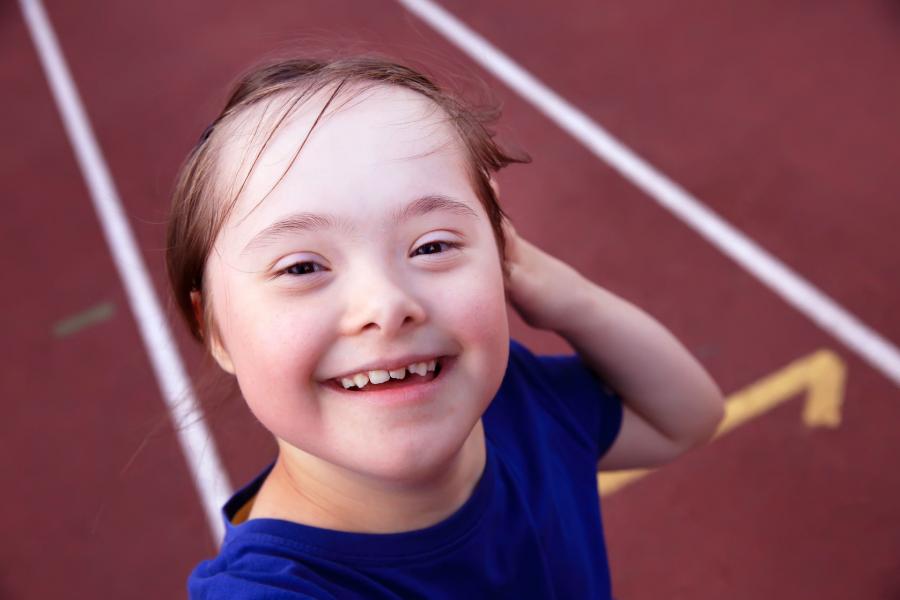 Young girl with disability smiling to camera while at the track in a stadium