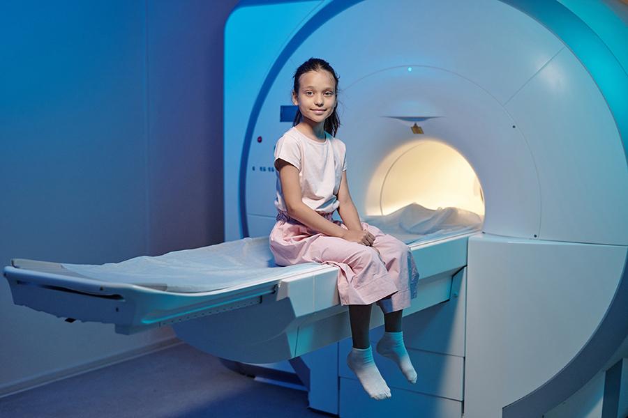 A child sitting in front of an MRI scanner