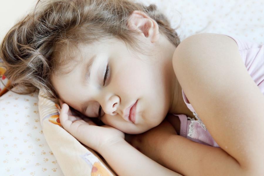 Close up of young girl asleep in bed