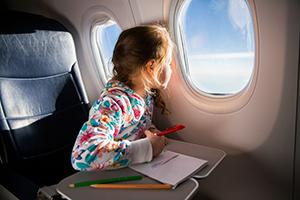 A child on an aeroplane looking out of the aeroplane window next to her seat