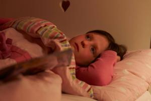 Worried young girl lying in bed awake at night